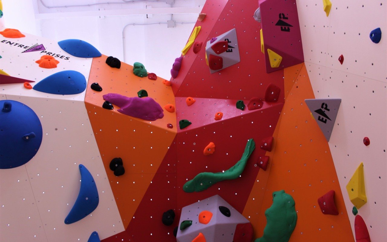 Symbolbild Bouldern/Klettern: Nahaufnahme einer bunten Kletterwand