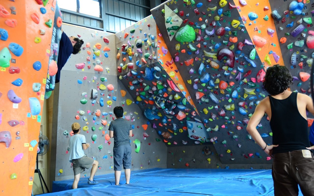 Symbolbild Bouldern/Klettern: Kletterer an einer bunten Boulderwand