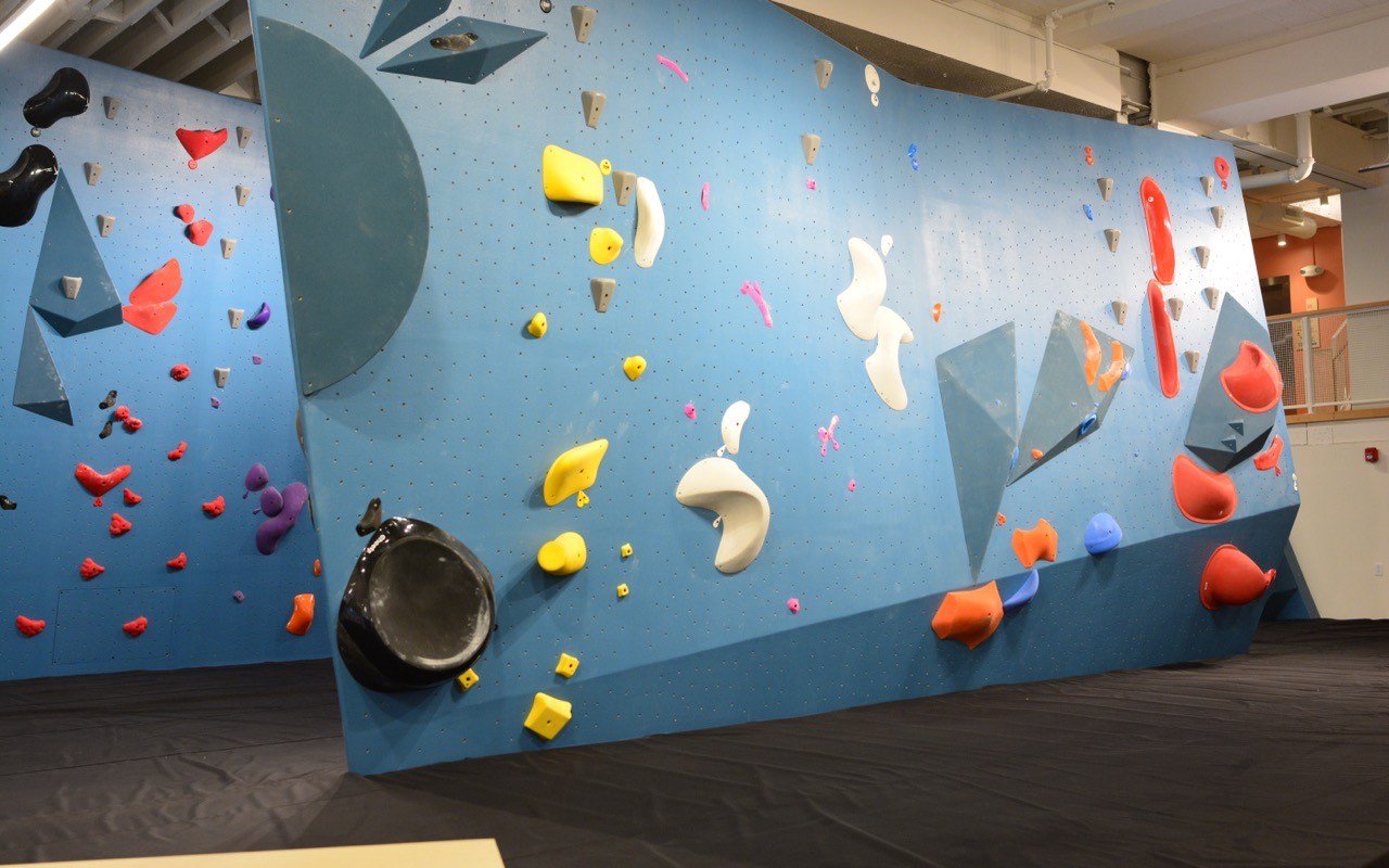 Symbolbild Bouldern/Klettern: Blaue Boulderwand mit bunten Griffen