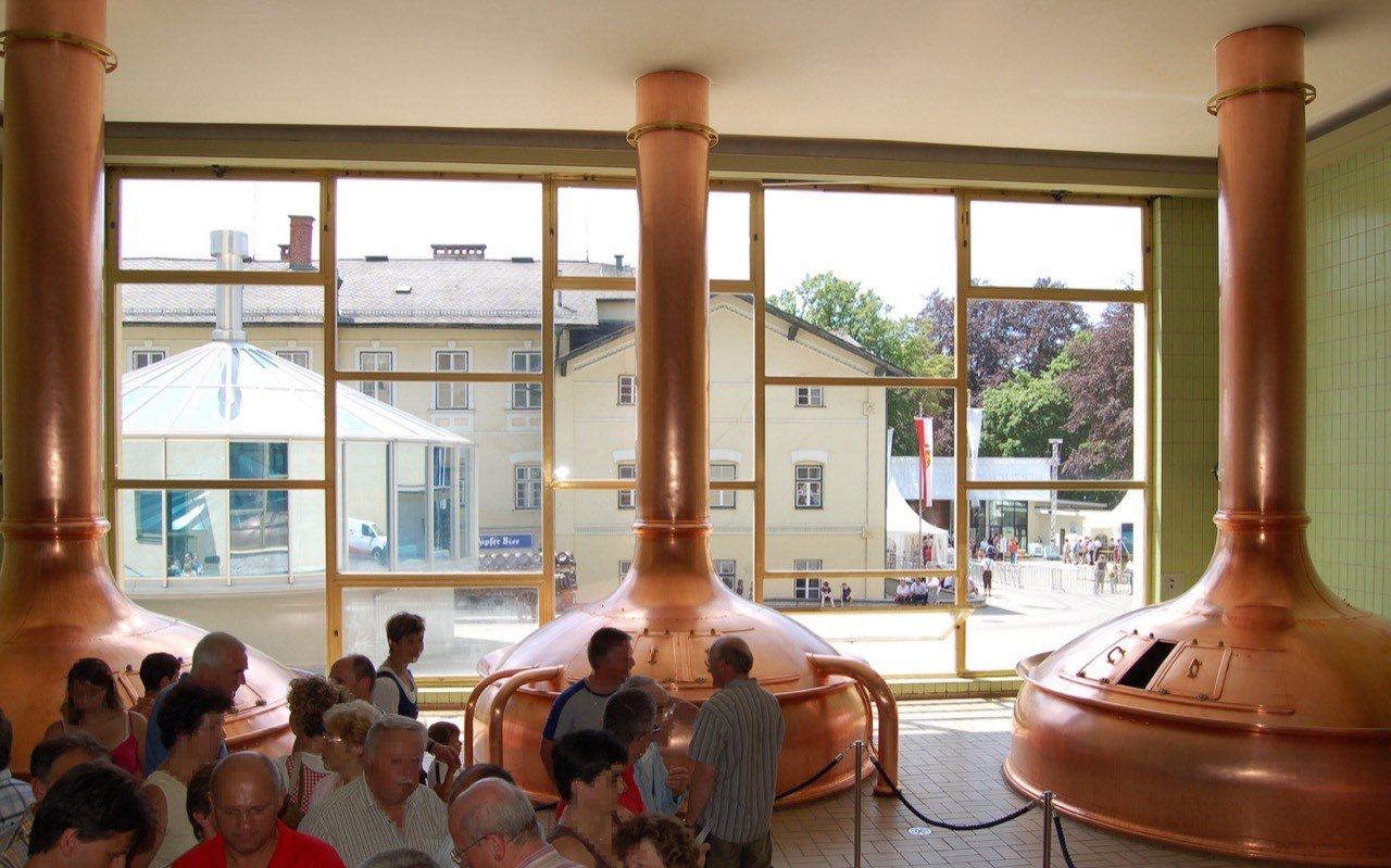 Symbolbild Brauerei/Bierverkostung: Besucher im Sudhaus mit Kupferkesseln