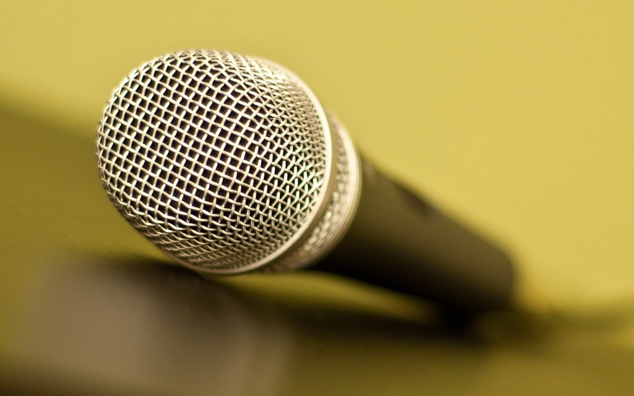 Symbolbild Karaoke: Silbernes Mikrofon in Nahaufnahme auf gelbem Hintergrund
