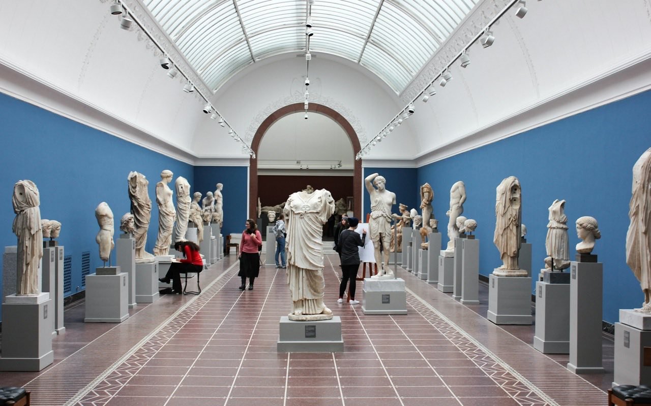 Symbolbild Museum: Besucher in heller Skulpturenhalle mit antiken Statuen